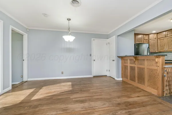 a view of an empty room with window and wooden floor