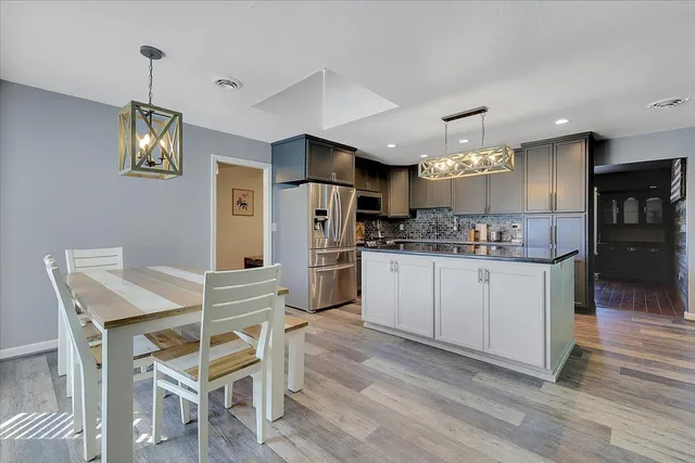 a kitchen with cabinets wooden floor and stainless steel appliances
