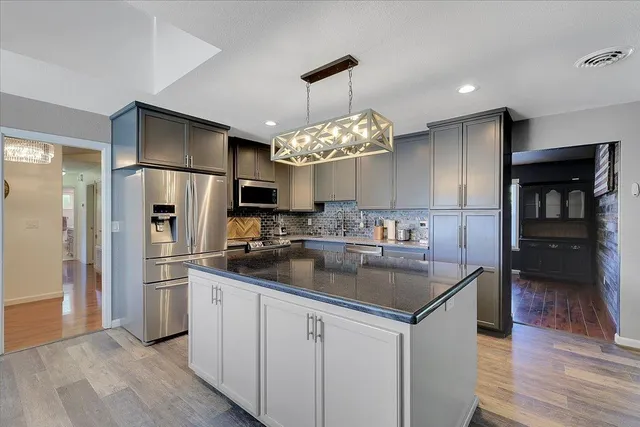 a kitchen with stainless steel appliances granite countertop a refrigerator and a sink