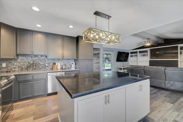 a kitchen with stainless steel appliances granite countertop a sink a stove and cabinets