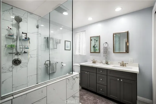 a bathroom with a double vanity sink mirror and shower
