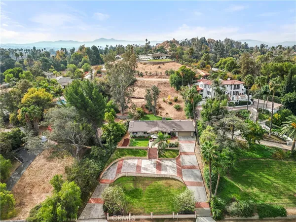 an aerial view of residential houses with outdoor space and trees
