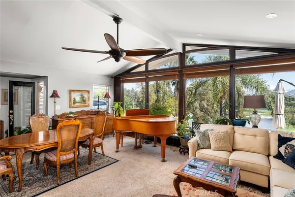 a living room with furniture a ceiling fan and a large window