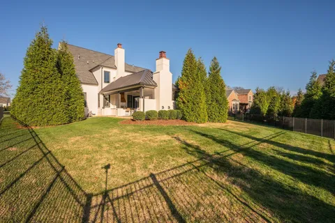 a view of a big house with a big yard and large trees