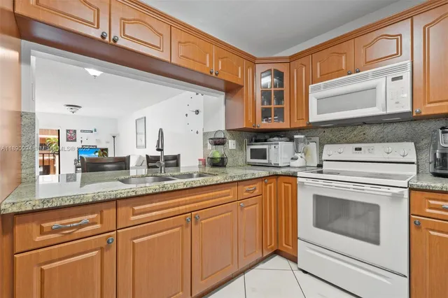 a kitchen with granite countertop a sink stainless steel appliances and cabinets