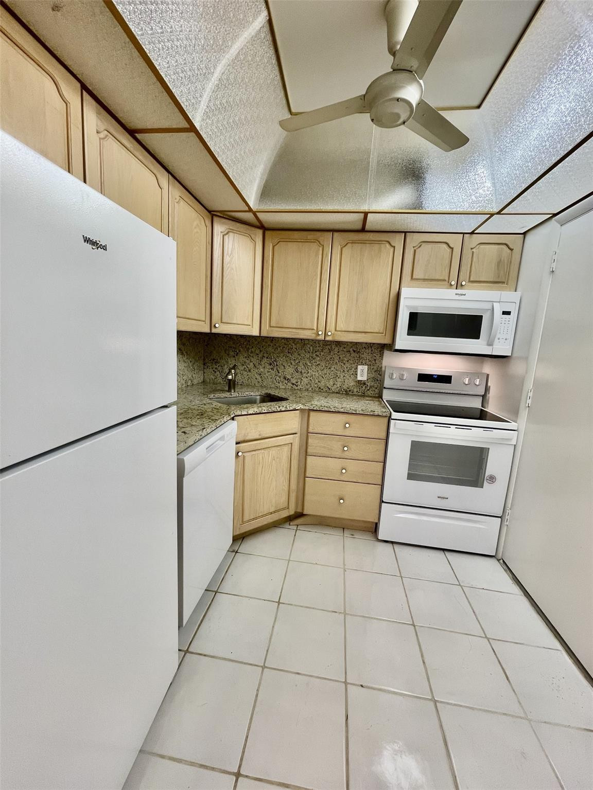 424 North Riverside Drive, Unit 102 Pompano Beach, FL 33062 - Photo 4 of 16 a kitchen with a stove a refrigerator and white cabinets
