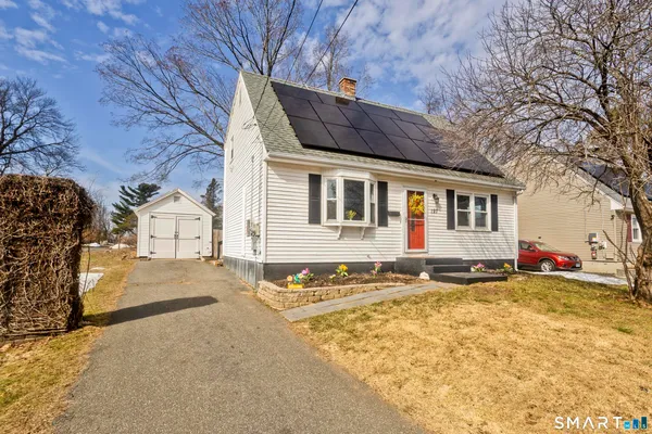 a view of a white house with a large tree in front of it