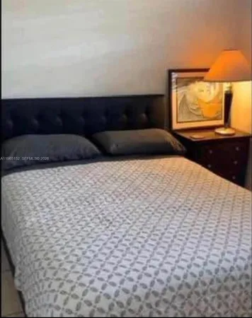 a bedroom with a bed and a lamp on dresser