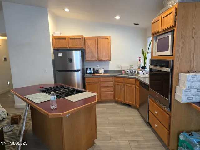 a kitchen with stainless steel appliances granite countertop a stove top oven a sink a refrigerator and white cabinets