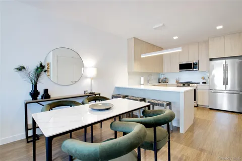 a kitchen with stainless steel appliances kitchen island a table chairs and a refrigerator