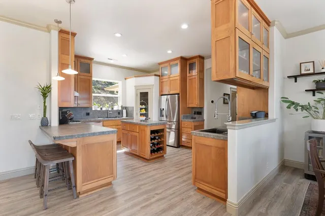 a kitchen with stainless steel appliances granite countertop a refrigerator a stove top oven a sink dishwasher and white cabinets with wooden floor