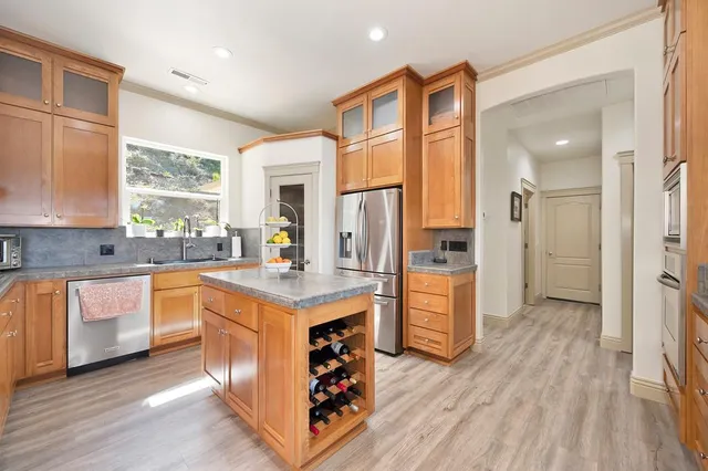 a kitchen with stainless steel appliances granite countertop a refrigerator a sink dishwasher a stove and white countertops with wooden floor