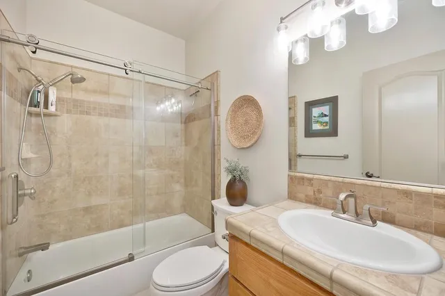 a bathroom with a sink a toilet a mirror a bathtub and shower