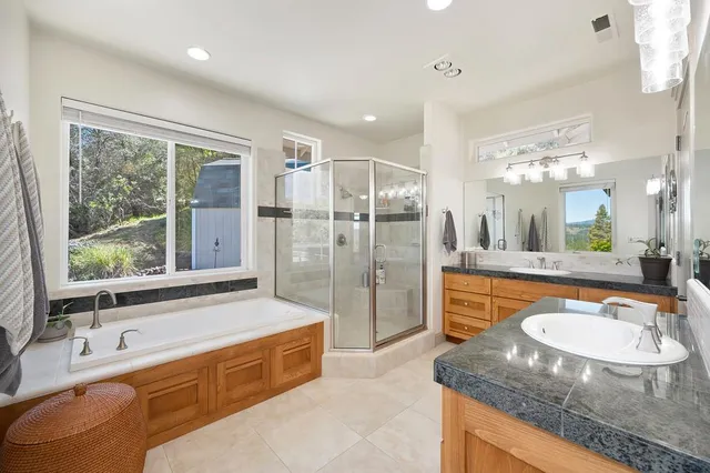 a bathroom with a granite countertop tub sink and mirror