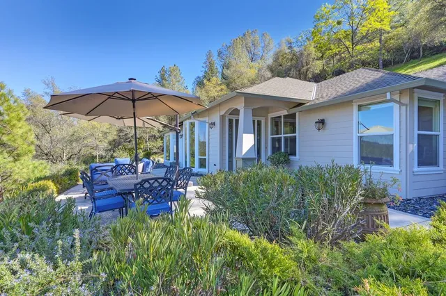 a view of a house with table and chairs under an umbrella