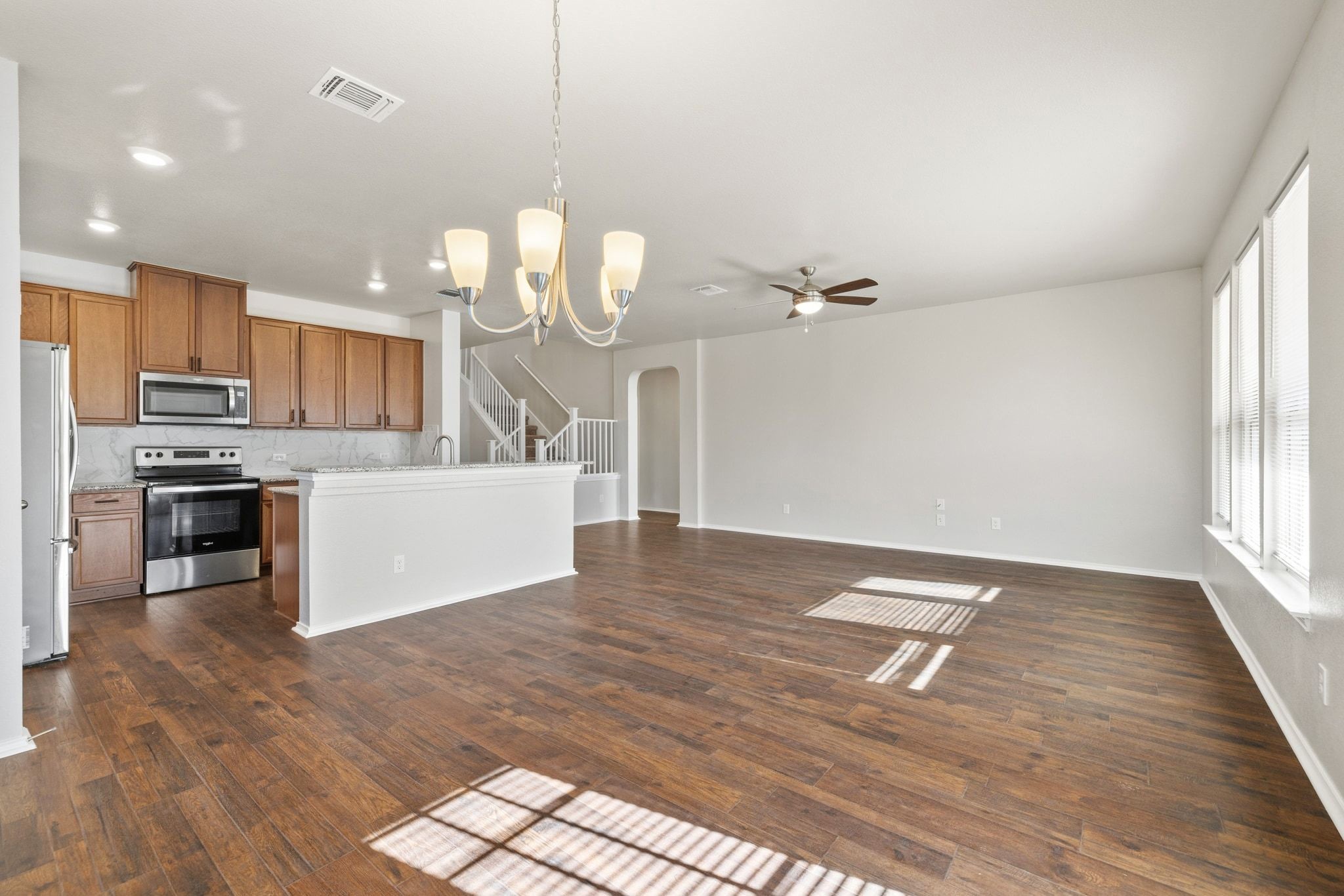 1829 Stringer Pass Leander, TX 78641 - Photo 35 of 36 Kitchen with a chandelier, open floor plan, stainless steel appliances, arched walkways, and dark wood-style floors