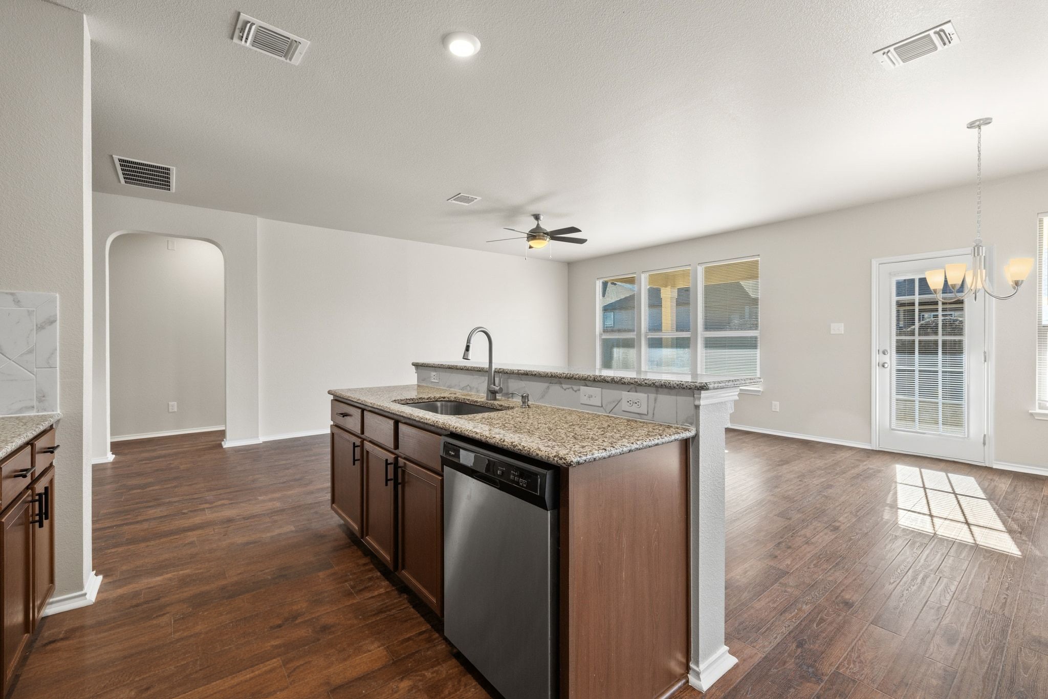 1829 Stringer Pass Leander, TX 78641 - Photo 36 of 36 Kitchen featuring arched walkways, open floor plan, a center island with sink, light stone counters, and dishwasher