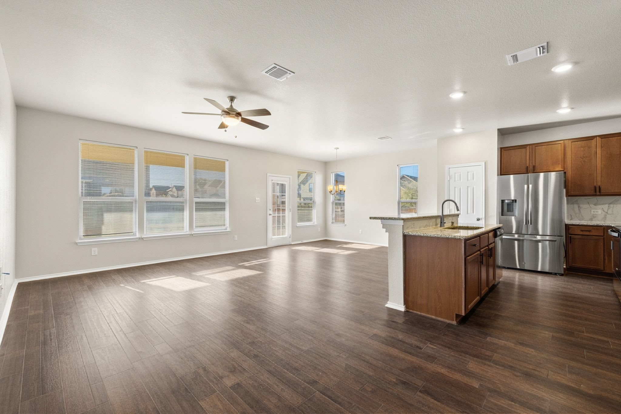 1829 Stringer Pass Leander, TX 78641 - Photo 34 of 36 Kitchen featuring open floor plan, stainless steel fridge with ice dispenser, a kitchen island with sink, wood finish cabinets, and recessed lighting