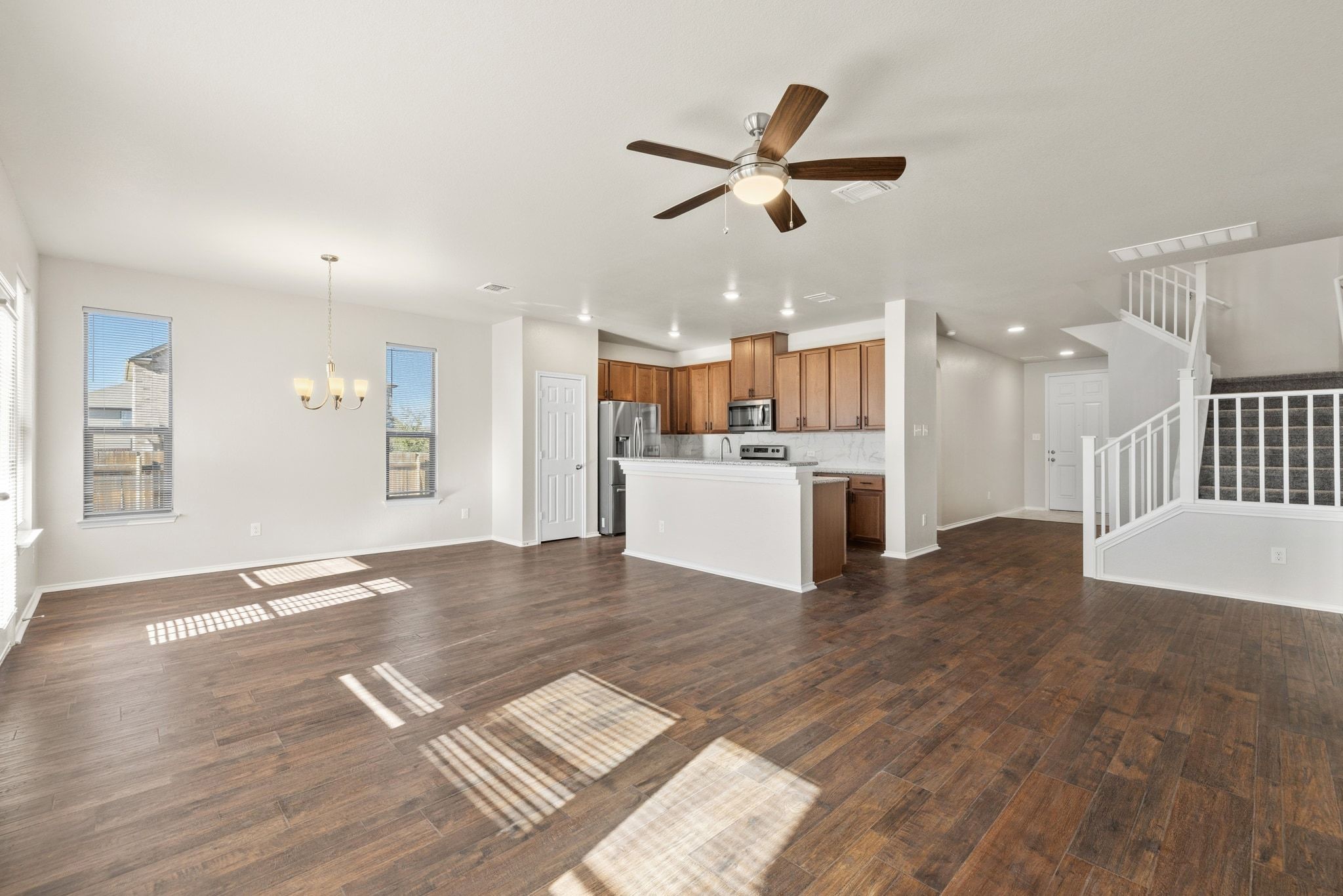 1829 Stringer Pass Leander, TX 78641 - Photo 8 of 36 Unfurnished living room featuring a ceiling fan, a chandelier, and dark wood-style flooring