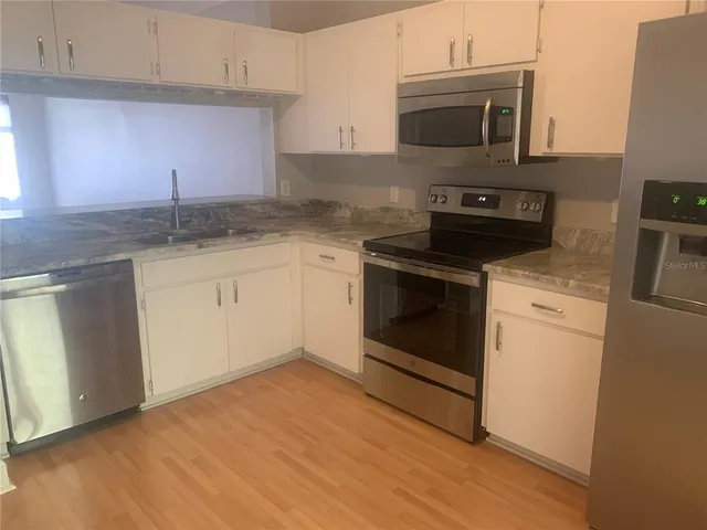 a kitchen with granite countertop cabinets stainless steel appliances and a sink