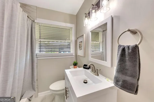 a bathroom with a sink a toilet and a window