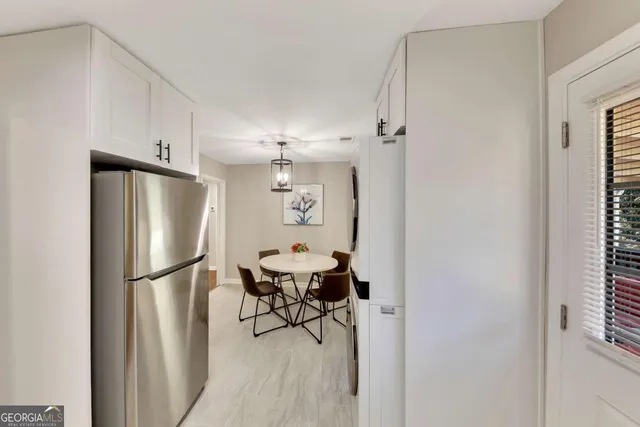 a kitchen with stainless steel appliances refrigerator dining table and chairs