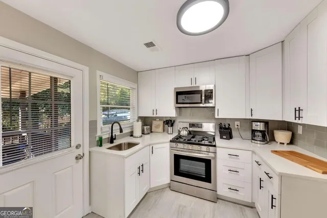 a kitchen with white cabinets stainless steel appliances and sink