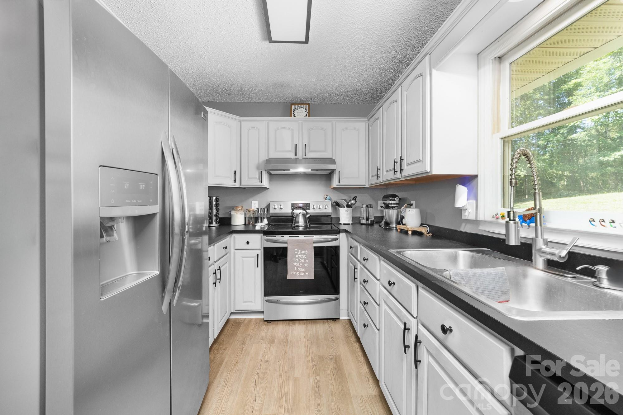 248 Jack McKinney Road Forest City, NC 28043 - Photo 24 of 29 a kitchen with granite countertop a sink a counter space stainless steel appliances cabinets and a large window