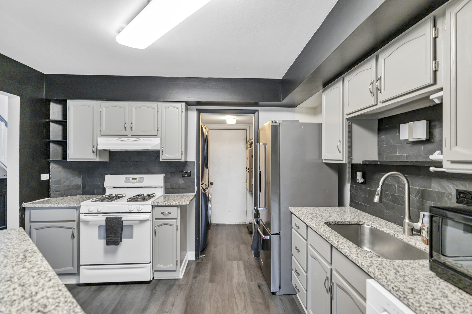 1941 Quaker Hollow Lane, Unit 1941 Streamwood, IL 60107 - Photo 6 of 13 a kitchen with stainless steel appliances granite countertop a sink stove a refrigerator and cabinets with wooden floor