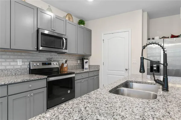 a kitchen with stainless steel appliances granite countertop a sink stove and refrigerator