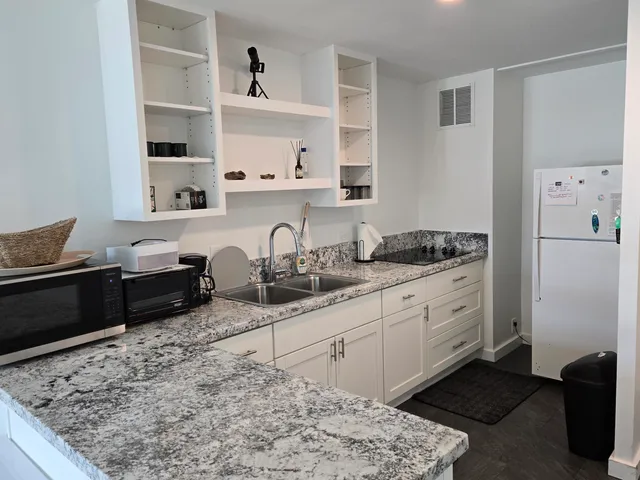 a kitchen with granite countertop white cabinets and refrigerator