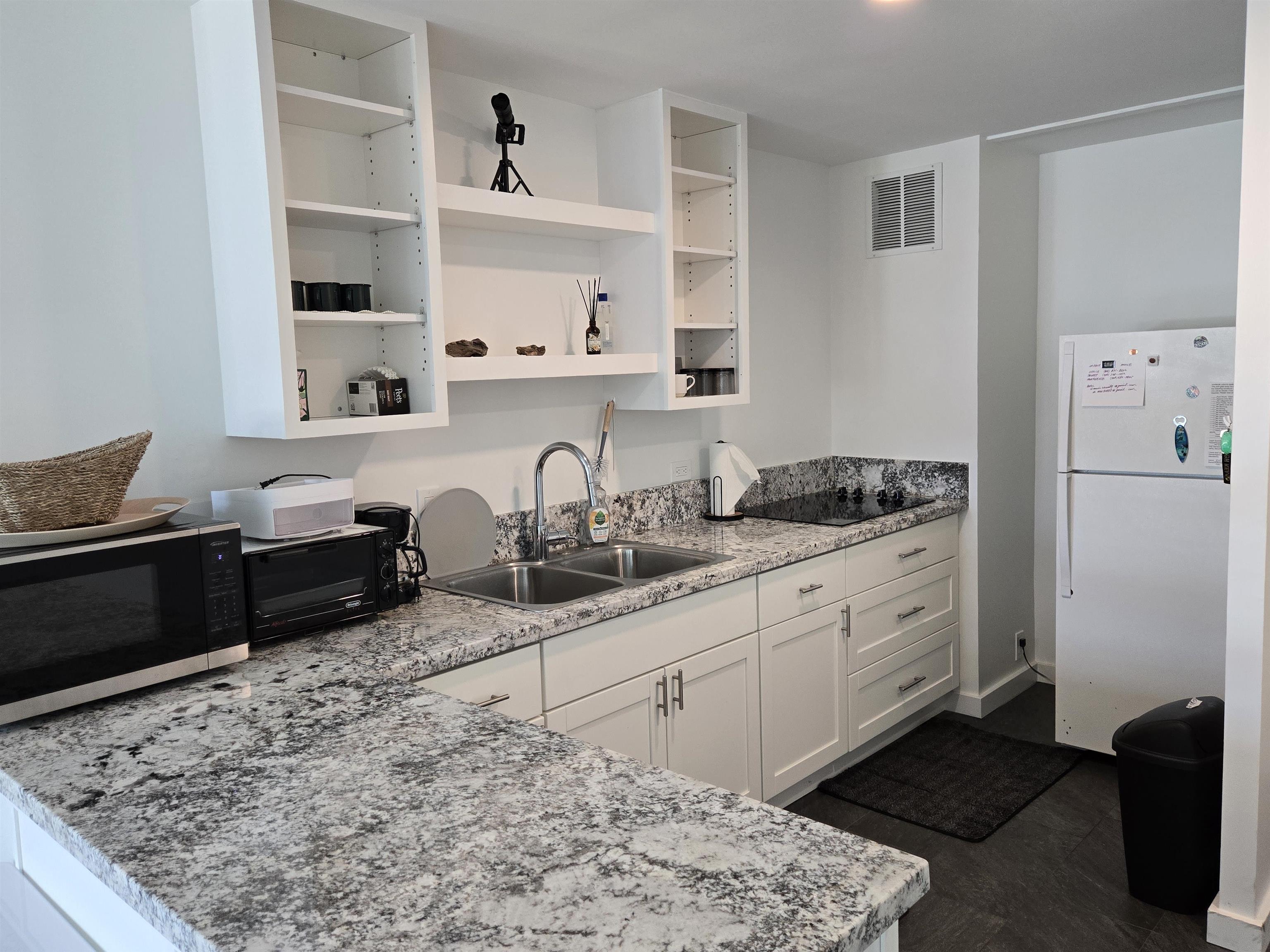 a kitchen with granite countertop white cabinets and refrigerator