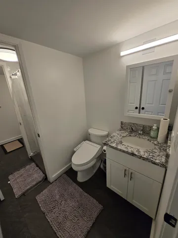 a spacious bathroom with a granite countertop sink a toilet a mirror and vanity