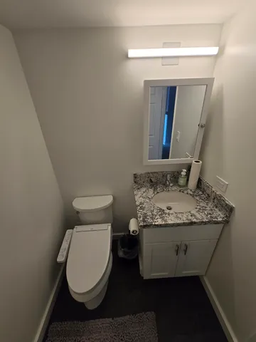 a bathroom with a granite countertop toilet and a sink