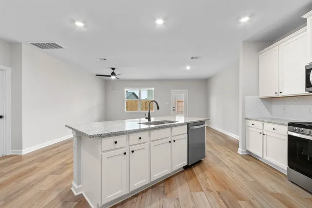 a kitchen with white cabinets appliances and wooden floor