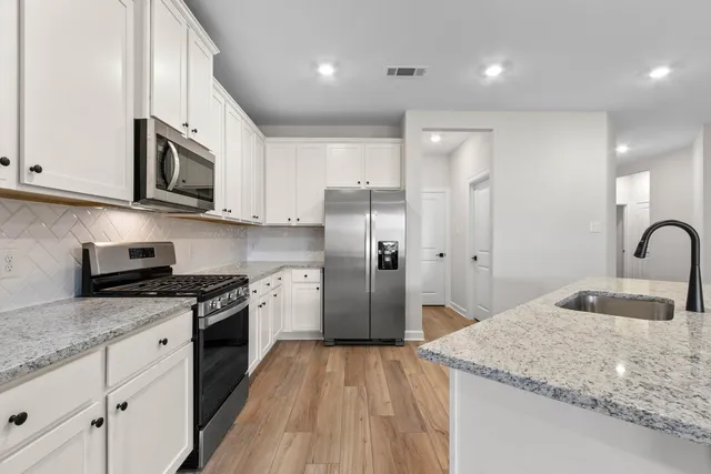 a kitchen with stainless steel appliances granite countertop a stove a sink and a refrigerator