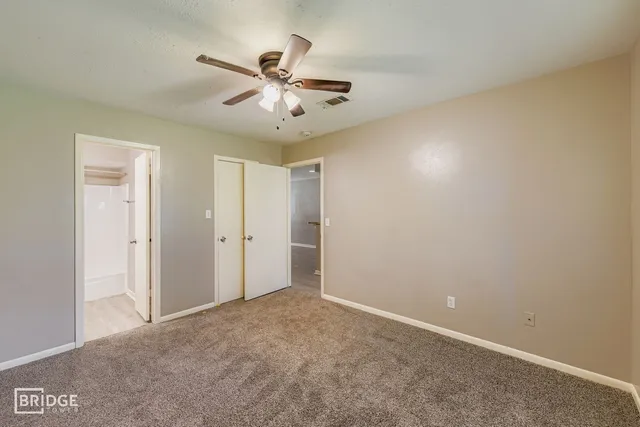 a view of a big room with a chandelier fan and windows