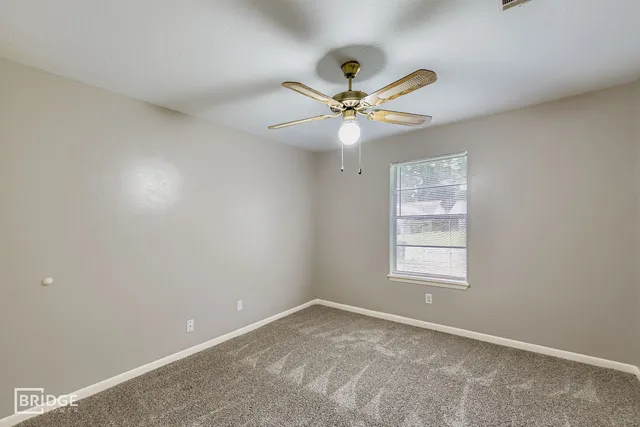 an empty room with a window and a fan