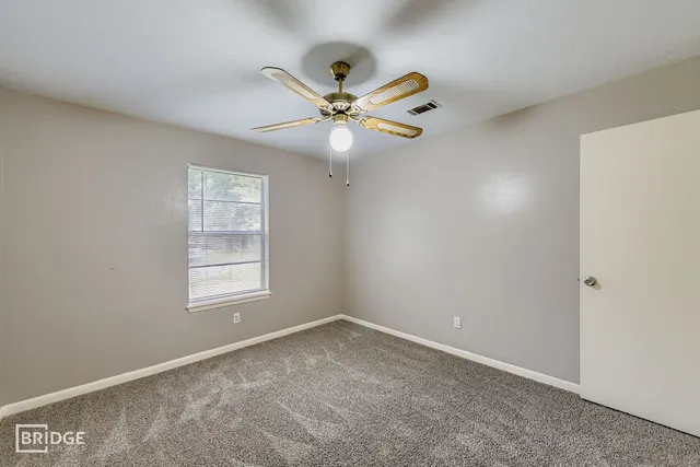 an empty room with windows and fan