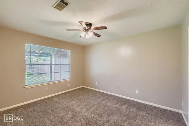 an empty room with windows and fan