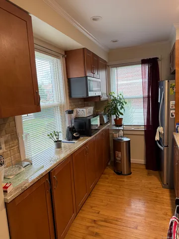 a kitchen with stainless steel appliances kitchen island granite countertop a refrigerator a sink dishwasher a stove a microwave oven with cabinets and wooden floor