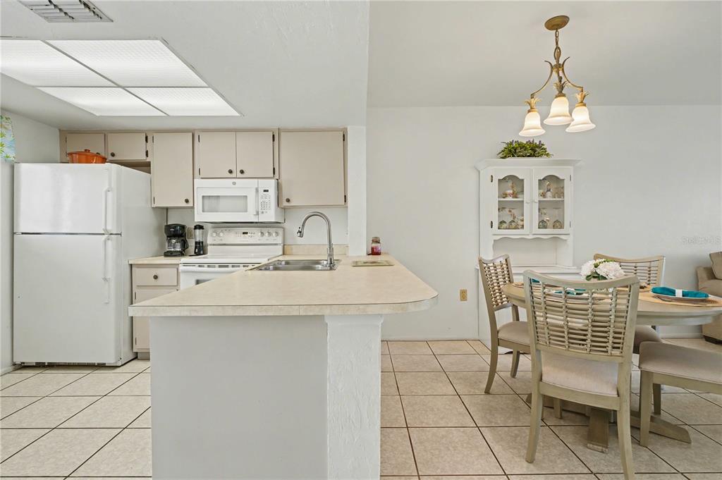 25225 Rampart Boulevard, Unit 1606 Punta Gorda, FL 33983 - Photo 10 of 34 a kitchen with kitchen island a stove a chandelier and a refrigerator