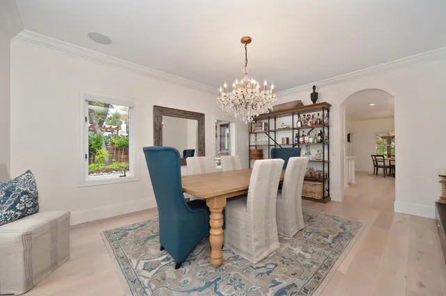 a view of a dining room and livingroom with furniture wooden floor a rug a painting and a chandelier