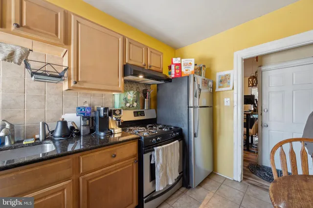 a kitchen with stainless steel appliances granite countertop a refrigerator a stove and a sink