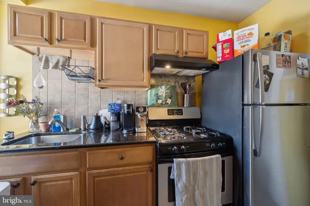 a kitchen with stainless steel appliances granite countertop a refrigerator and a stove top oven