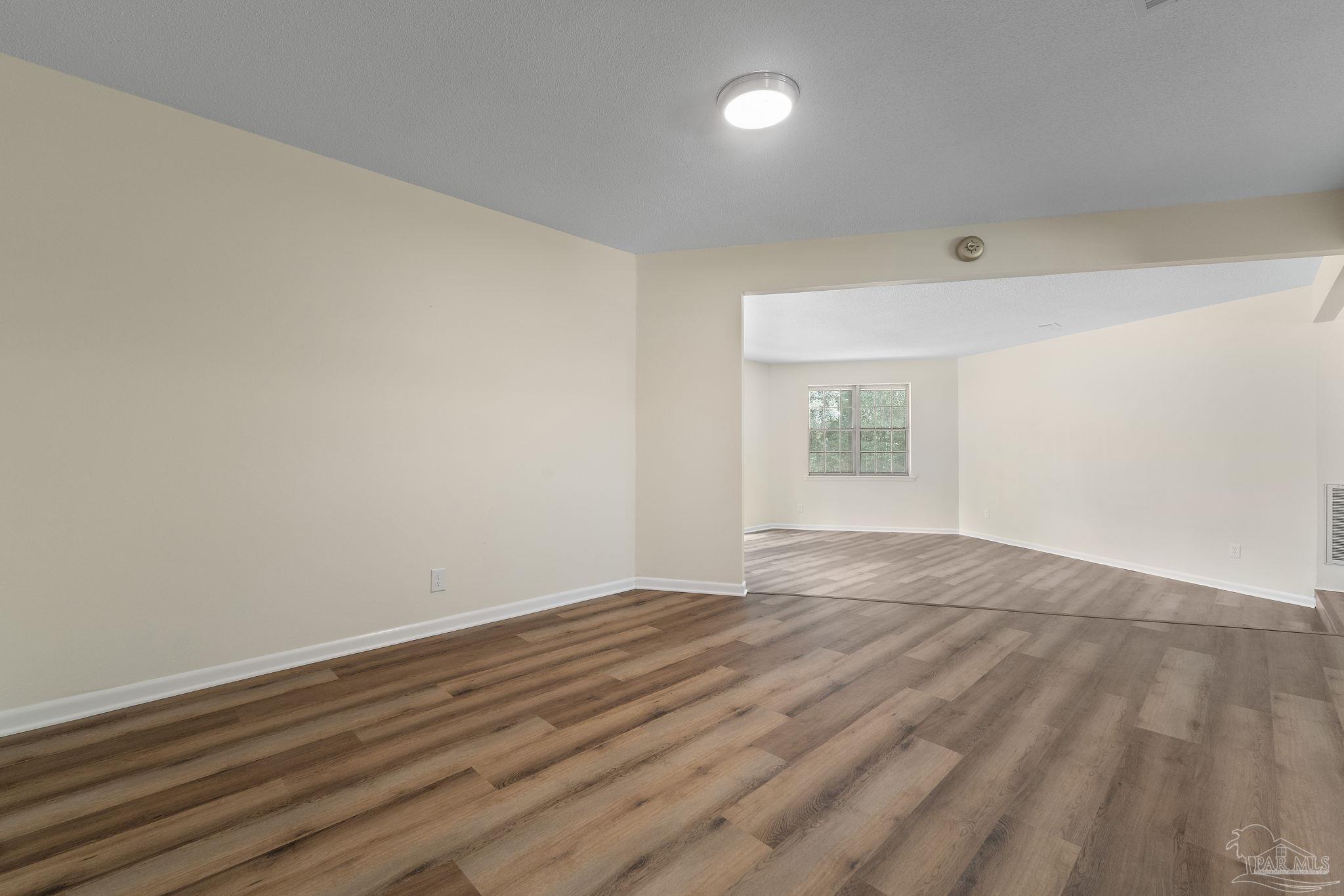 6472 Sandy Lane Milton, FL 32570 - Photo 10 of 51 a view of an empty room with wooden floor and a window