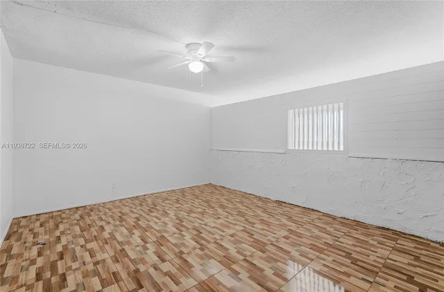 a view of a big room with wooden floor and chandelier fan