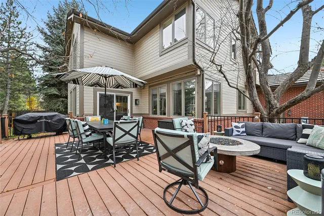 a view of a patio with couches table and chairs under an umbrella with wooden floor