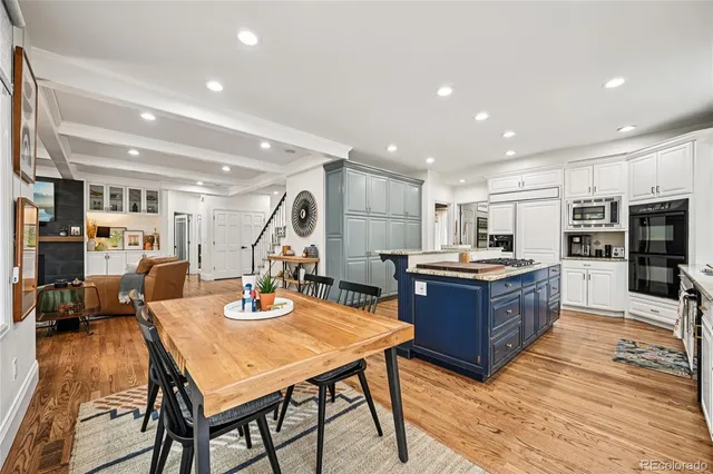 a kitchen with stainless steel appliances kitchen island granite countertop a table chairs and a refrigerator