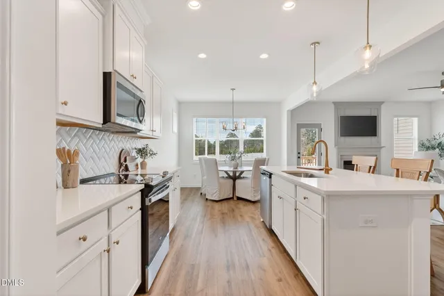 a kitchen with stainless steel appliances a sink stove and wooden floor